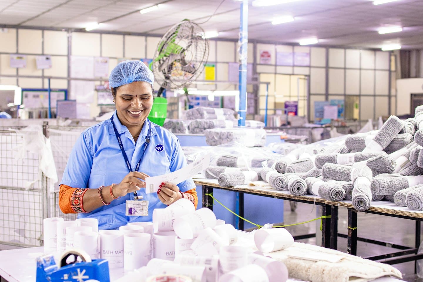 Lavoratore sorridente mentre ispeziona un documento a una postazione di lavoro.